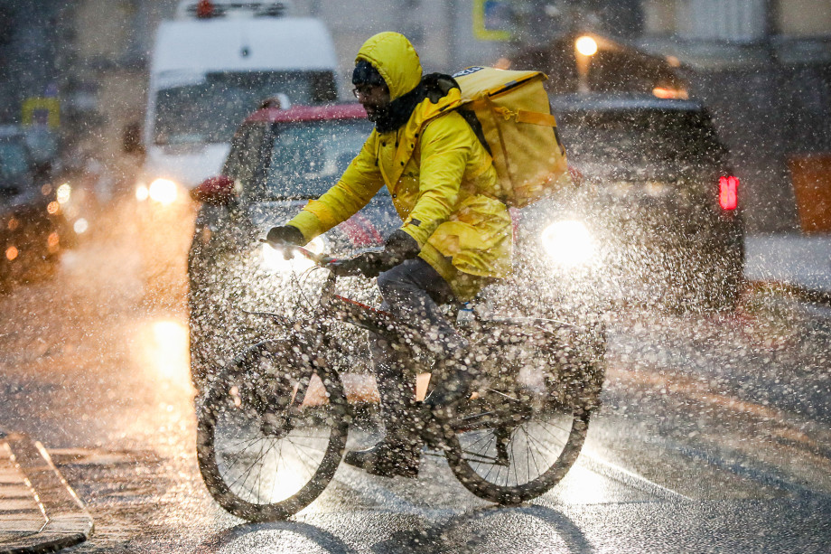 Курьер на велосипеде едет под дождем